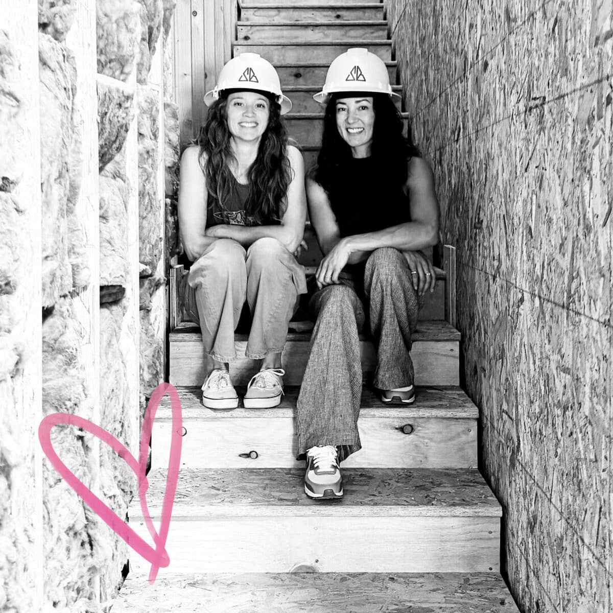 Gretchen and Lara sitting on the stairs in hard hats